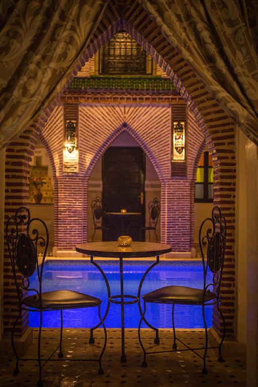 a table and two chairs in front of a brick wall at Riad Challa Hotel & Spa in Marrakesh