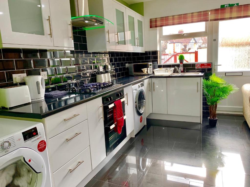 a kitchen with white cabinets and a washer and dryer at London 2 Bedroom Apartment, Kitchen, Reception and Private Garden in London