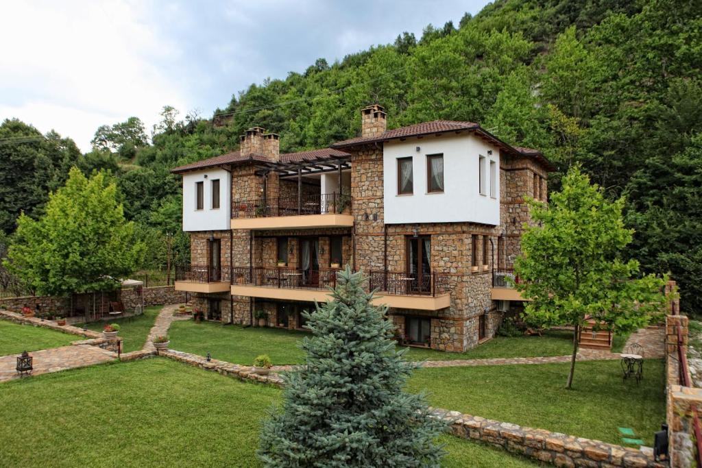 uma grande casa de pedra no meio de um quintal em Archontiko Emmanouilidi Suites em Kato Loutraki