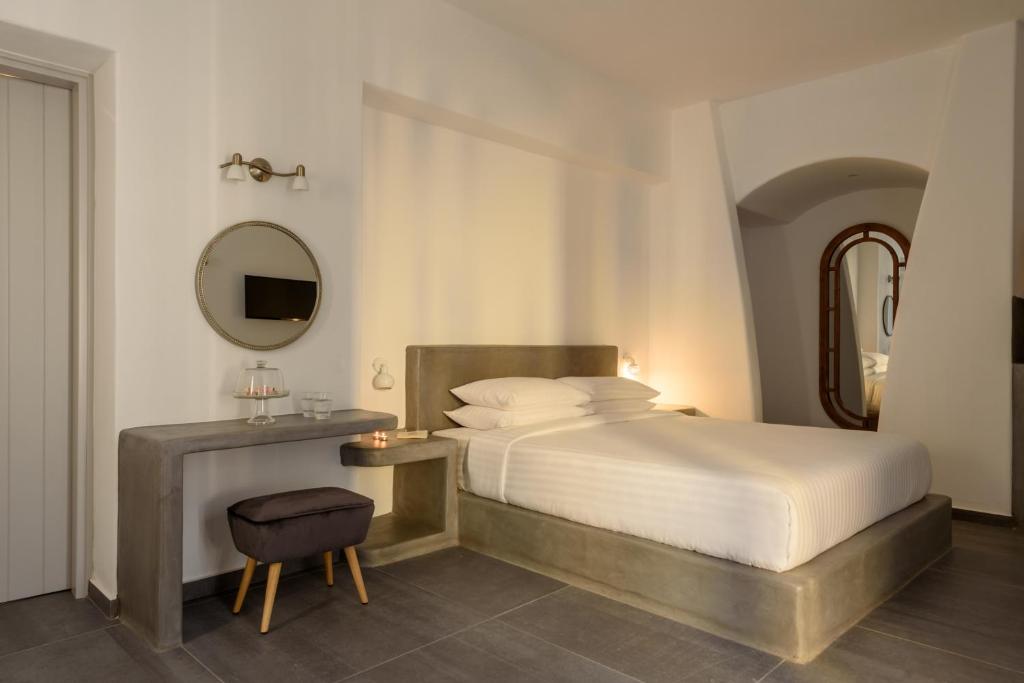 a bedroom with a bed and a mirror and a stool at Elitoz Suites in Oia