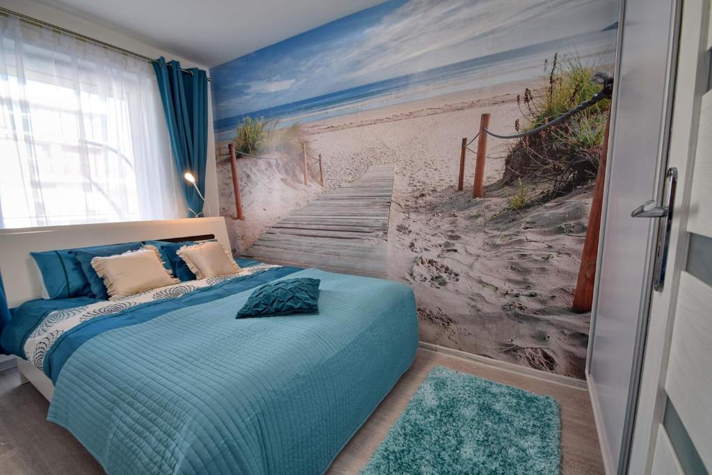 a bedroom with a blue bed with a painting of a staircase at Apartament Lazurowa Przystań Amber Sand w Kołobrzegu in Kołobrzeg
