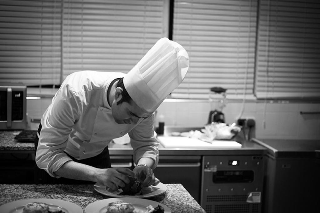 a man wearing a chefs hat preparing food in a kitchen at Riad Challa Hotel & Spa in Marrakesh