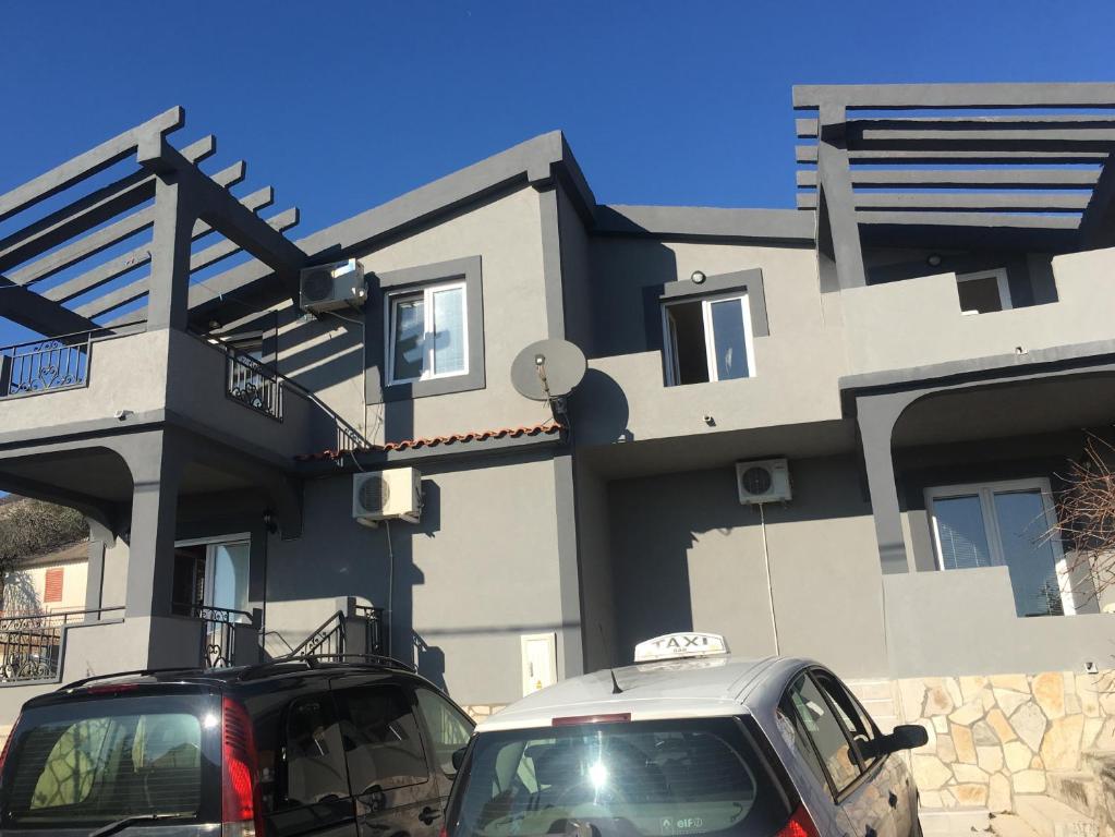 twee auto's geparkeerd voor een huis bij Apartmani Miljana in Bar