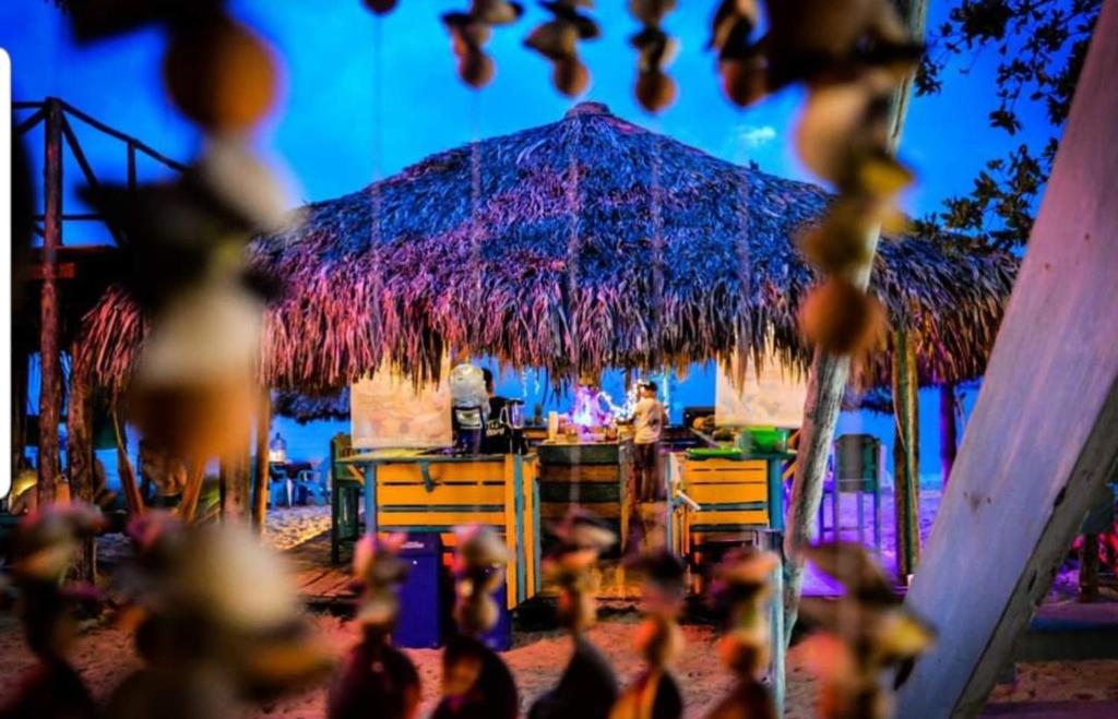 een tafel met een rieten parasol op een strand bij The Wizard & Bar BARU in Playa Blanca