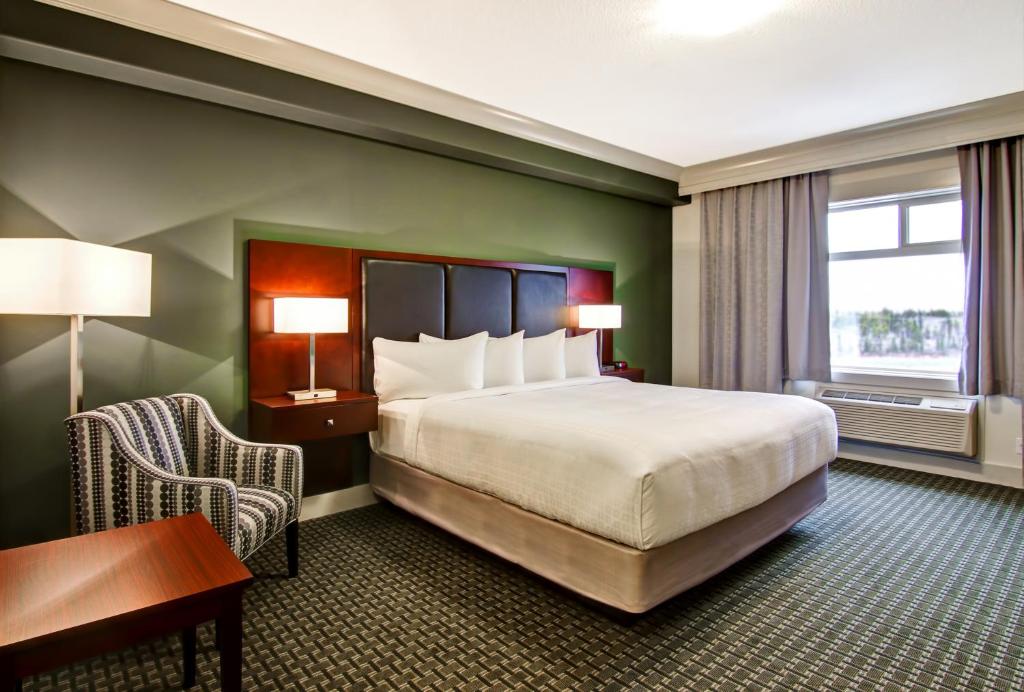 um quarto de hotel com uma cama, uma secretária e uma janela em Chateau Nova Yellowknife em Yellowknife