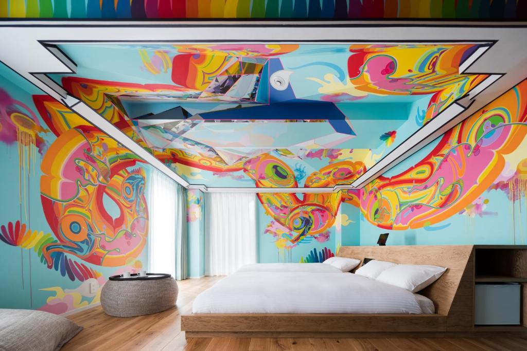 a bedroom with a colorful mural on the ceiling at BnA Alter Museum in Kyoto