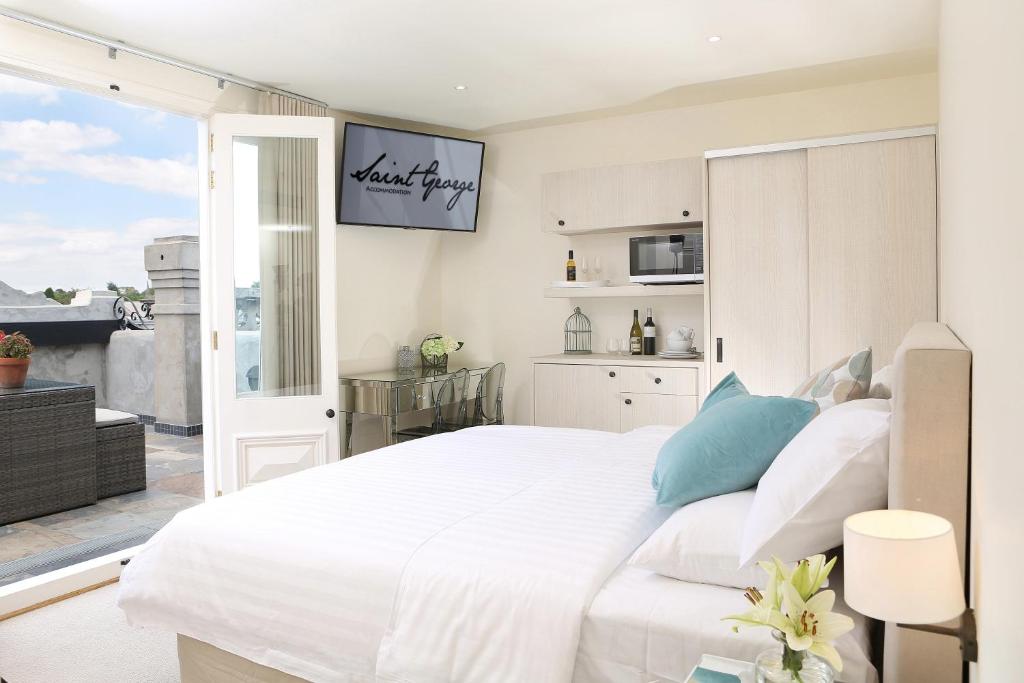 a bedroom with a large white bed and a balcony at Studio 8 - Penthouse in Melbourne