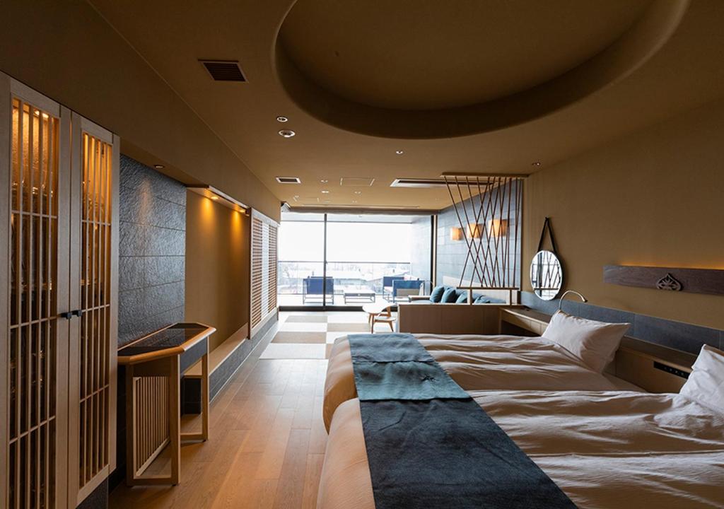une chambre avec un grand lit et une grande fenêtre dans l'établissement Lake Shikotsu Tsuruga Bessou AO no ZA, à Chitose