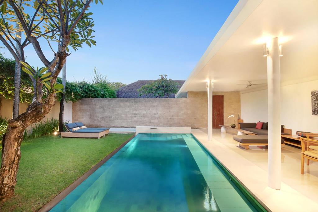 an infinity pool in a backyard with a house at Uma Sapna in Seminyak