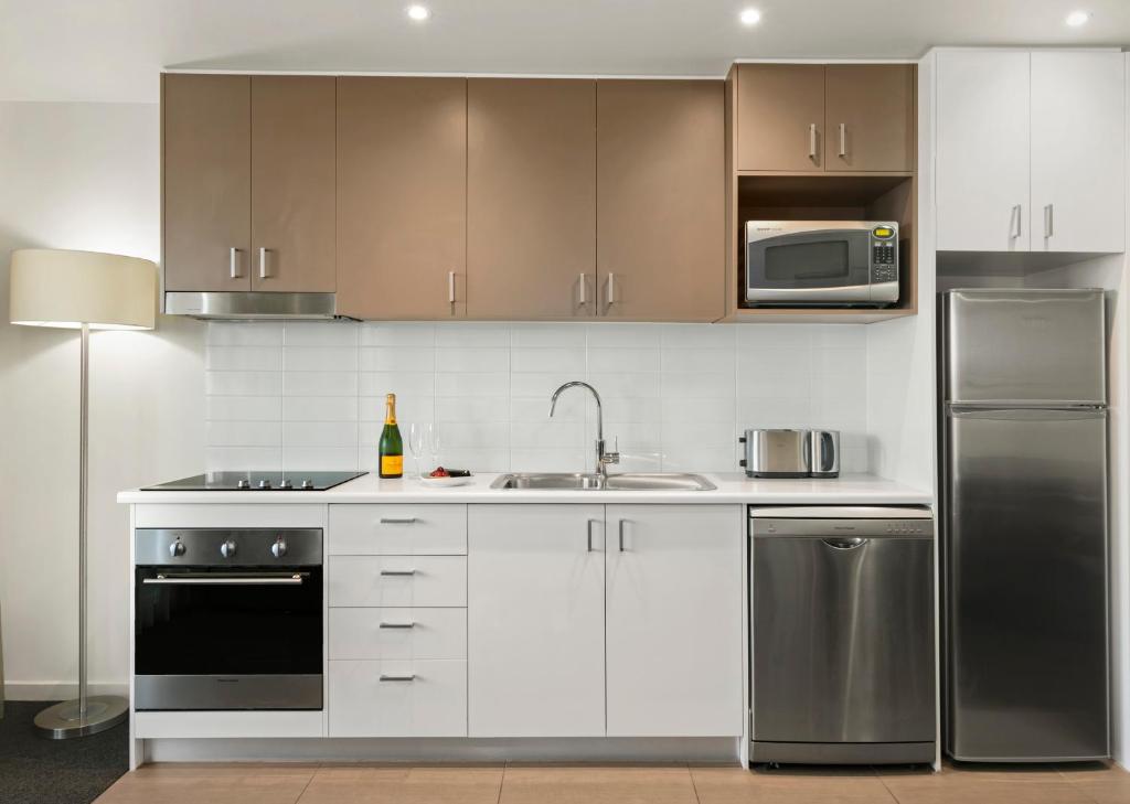 a kitchen with white cabinets and stainless steel appliances at Quest Cheltenham in Cheltenham