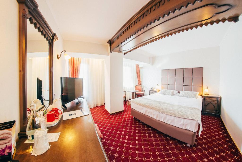 a bedroom with a large bed and a red rug at Best Western Bucovina Club de Munte in Gura Humorului