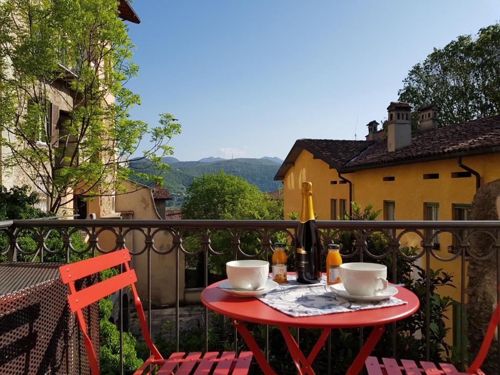 a red table with two chairs and two cups on a balcony at Bergamo Alta Guest House in Bergamo