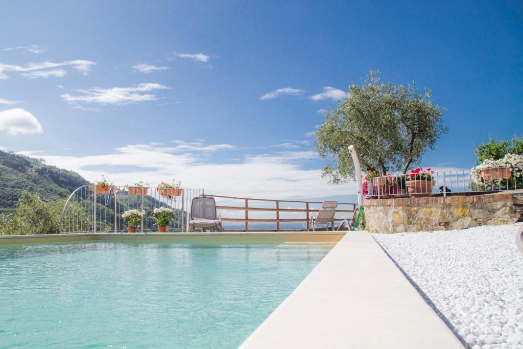 a swimming pool with blue water and a fence at Podere Scoglio d'Oro in Pescia