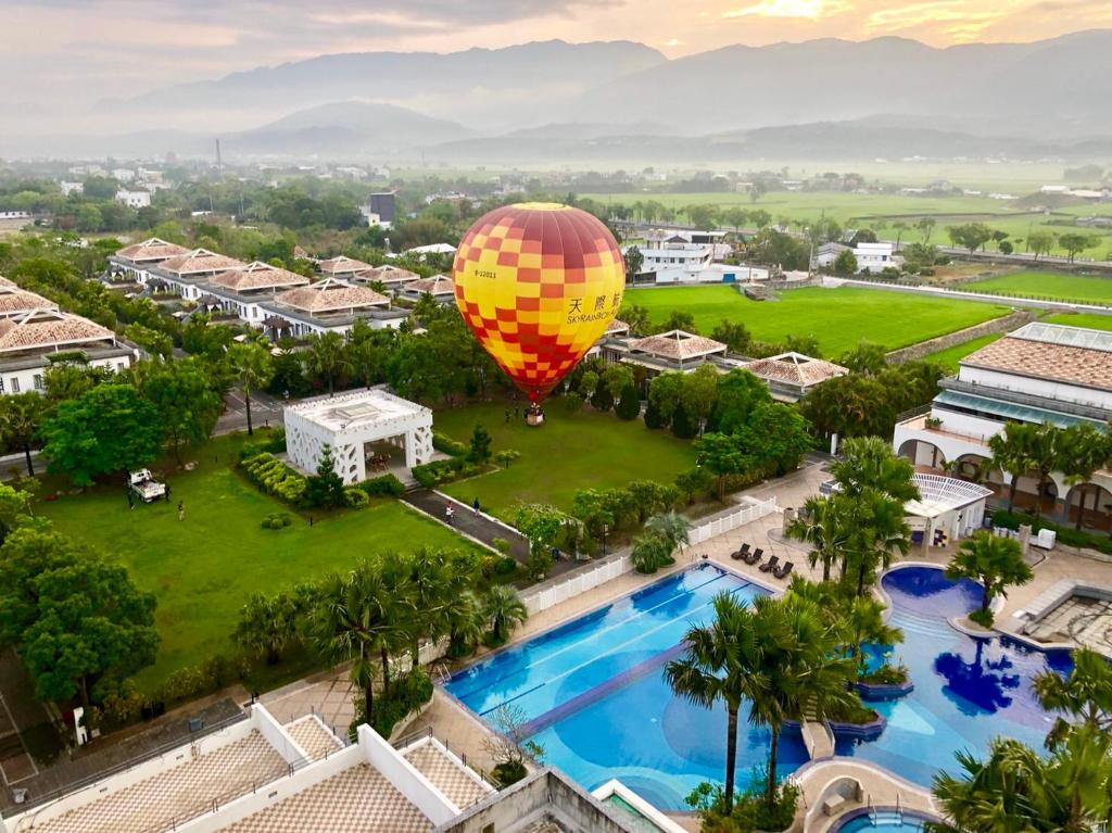 a hot air balloon flying over a resort with a pool at Papago International Resort in Chishang