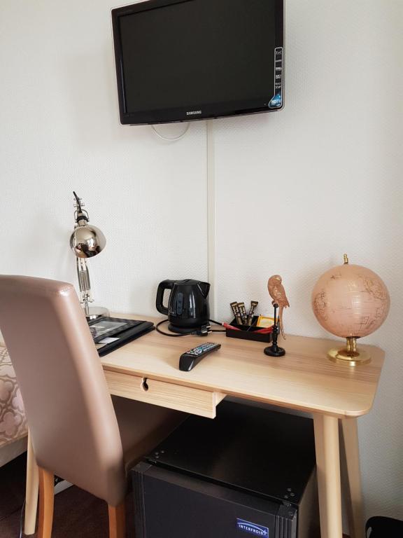 a wooden desk with a television on a wall at Hôtel L'ideal le Mountbatten in Arromanches-les-Bains