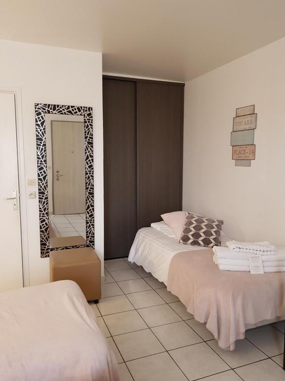 a bedroom with two beds and a mirror in it at Hôtel L'ideal le Mountbatten in Arromanches-les-Bains