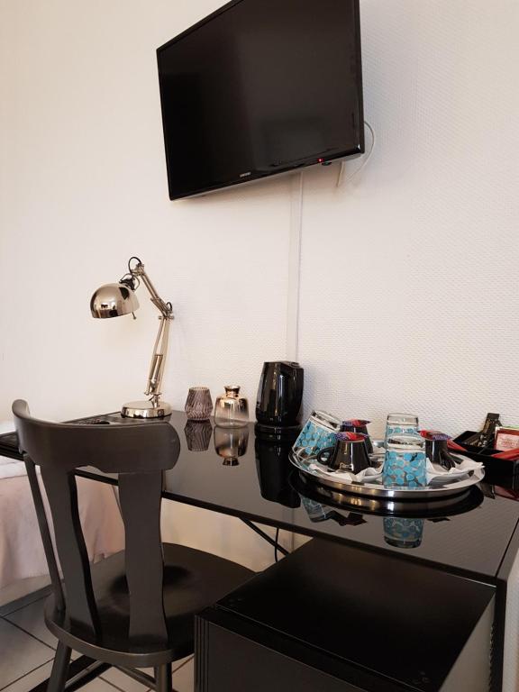 a desk with a chair and a television on a wall at Hôtel L'ideal le Mountbatten in Arromanches-les-Bains