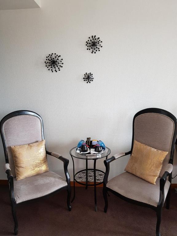 two chairs and a table in a room at Hôtel L'ideal le Mountbatten in Arromanches-les-Bains