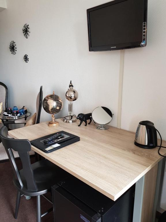a wooden desk with a television on a wall at Hôtel L'ideal le Mountbatten in Arromanches-les-Bains