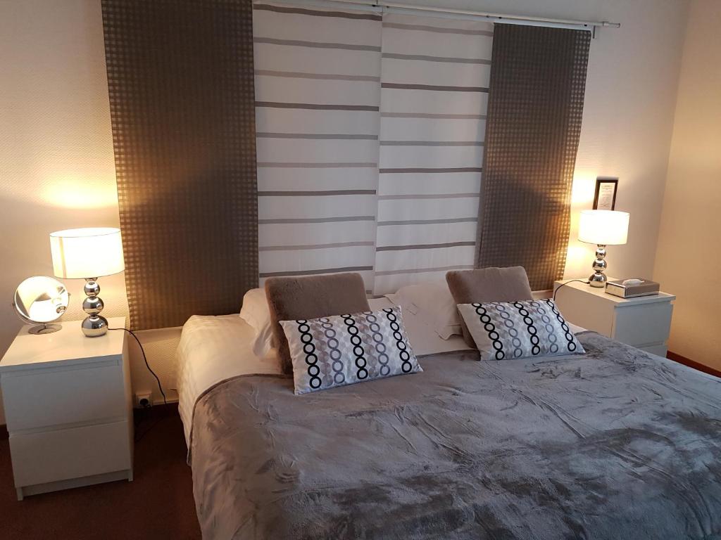 a bedroom with a large bed with two tables and two lamps at Hôtel L'ideal le Mountbatten in Arromanches-les-Bains