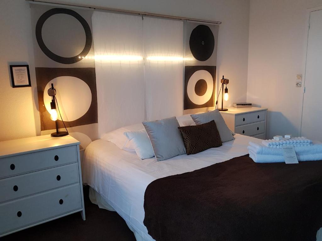a bedroom with a bed with two dressers and two lamps at Hôtel L'ideal le Mountbatten in Arromanches-les-Bains