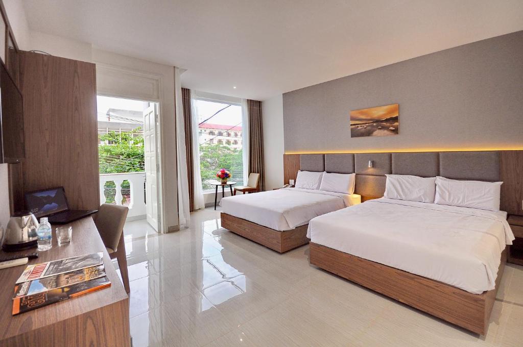 a bedroom with two beds and a desk and a television at For You Hotel in Nha Trang