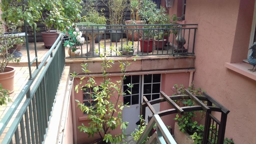 uma varanda com vasos de plantas num edifício em la maison rose: lieu atypique em Nemours