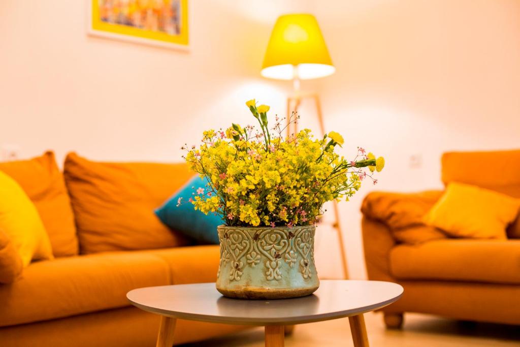 a vase of yellow flowers on a table in a living room at Yellow apartment in Avlabari in Tbilisi City