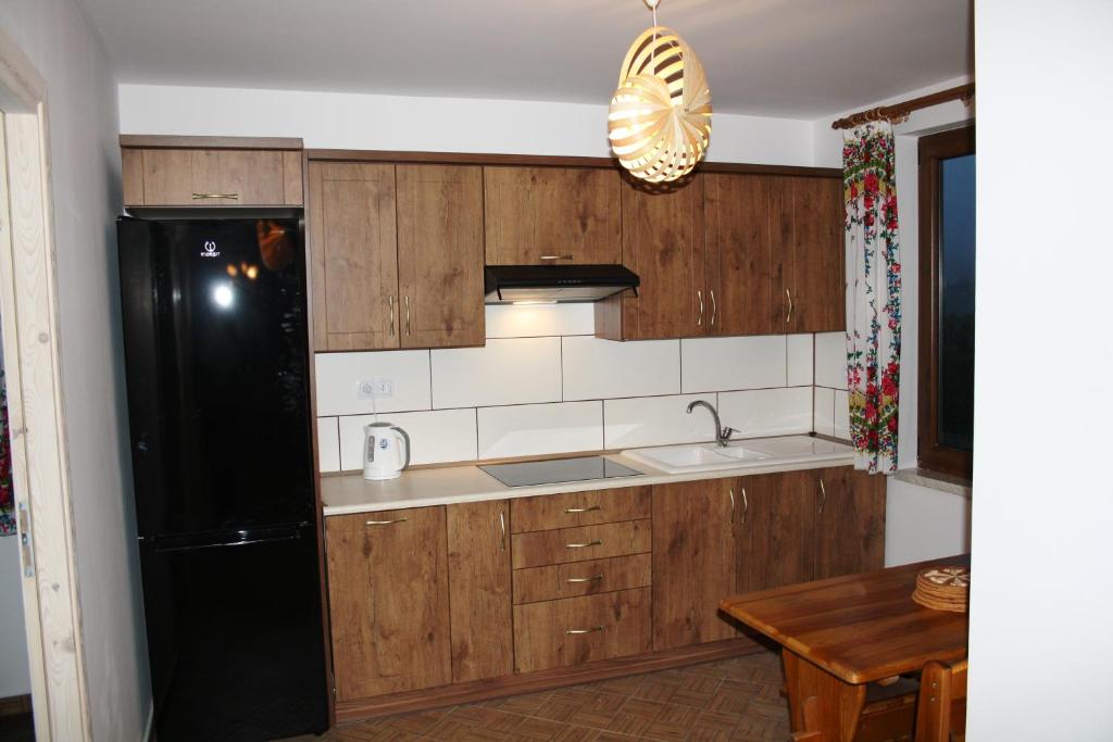 a kitchen with wooden cabinets and a black refrigerator at Leśny Dworek 1 in Wołkowyja