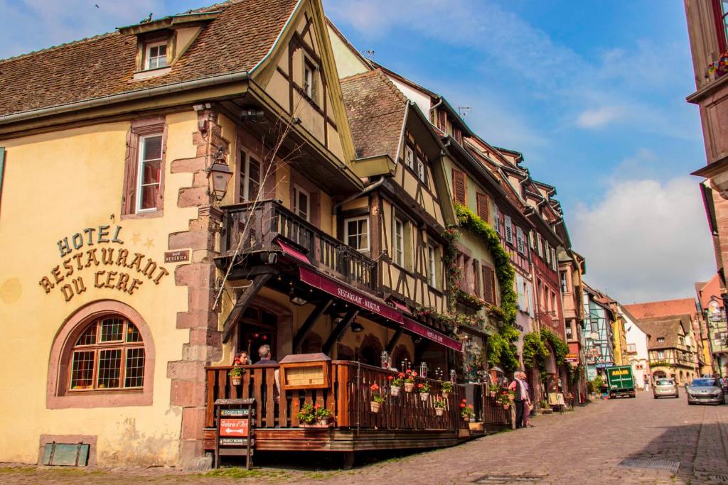 a building on a street with people standing outside of it at Hotel Au Cerf in Riquewihr