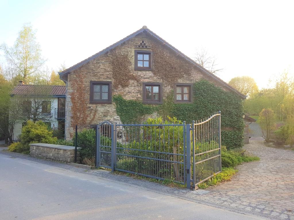 a brick house with a blue gate in front of it at Ancien moulin de Vaux Chavanne in Manhay