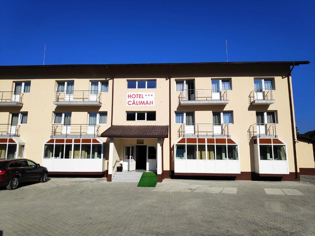 a large building with a parking lot in front of it at Hostel Caliman in Caciulata