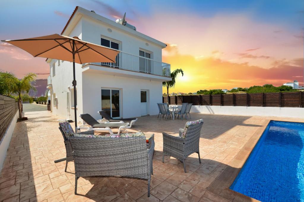 a villa with a swimming pool and a patio with an umbrella at Nissi Villa Ourania in Ayia Napa