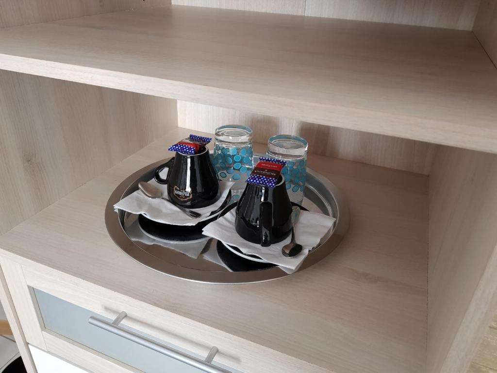a tray with three drinks on a plate in a cabinet at Hôtel L'ideal le Mountbatten in Arromanches-les-Bains