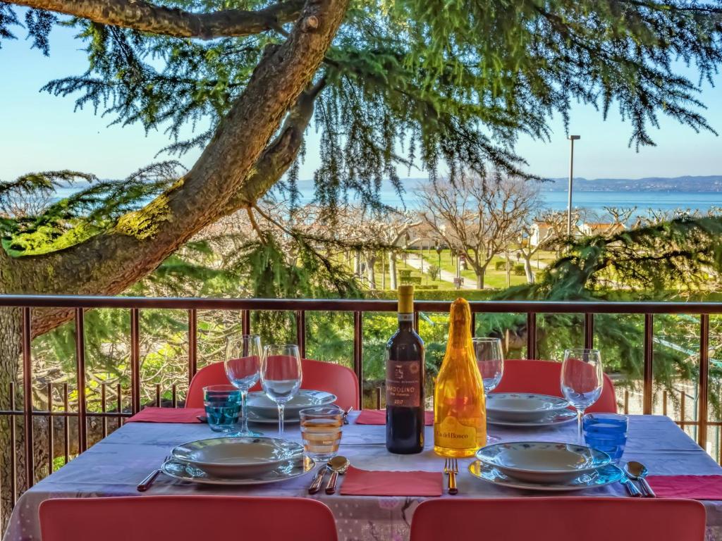una mesa con botellas de vino y copas en el balcón en Cabà Holiday Bardolino Santa Cristina, en Bardolino