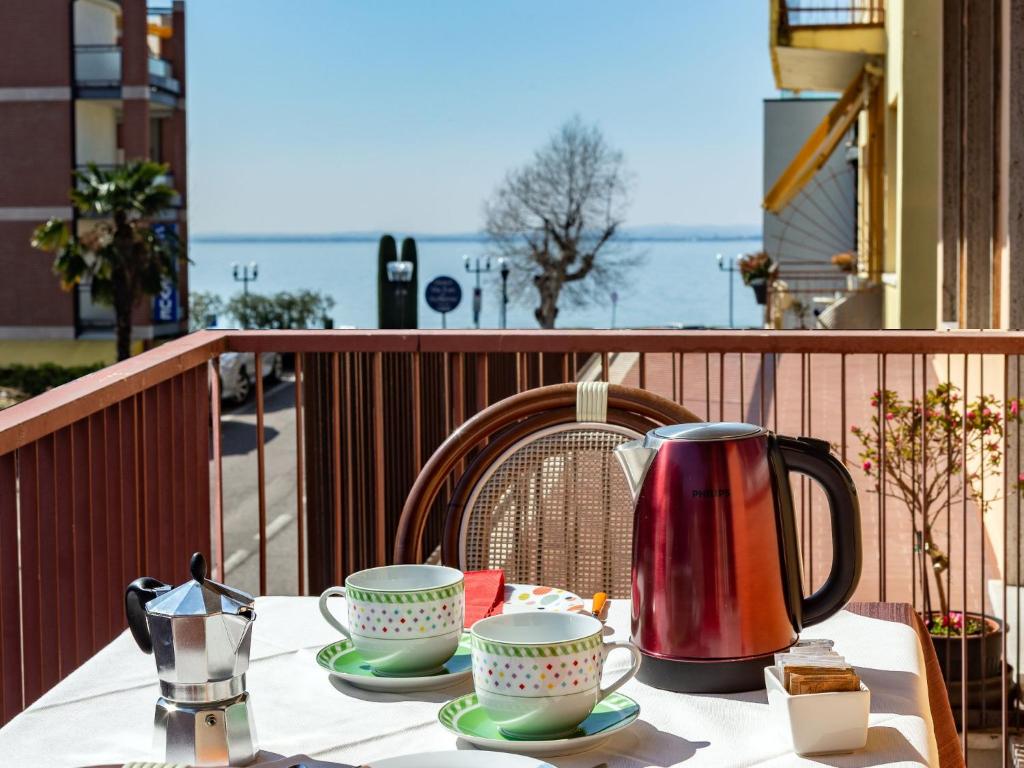 a table with a tea kettle and cups on a balcony at Cabà Holiday Bardolino D'Annunzio in Bardolino