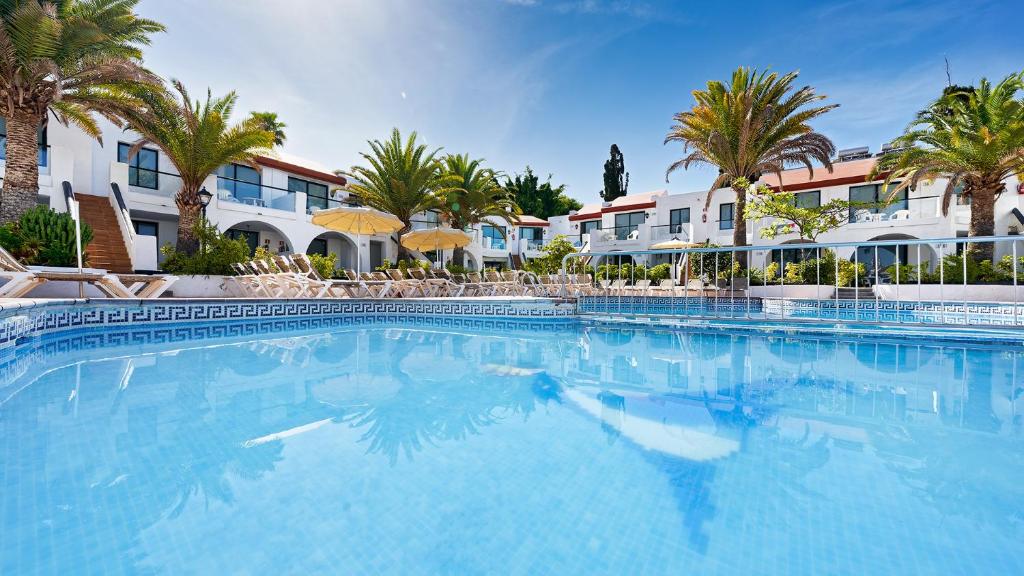 a large swimming pool with palm trees and buildings at Ura Nido del Águila in Puerto Rico de Gran Canaria