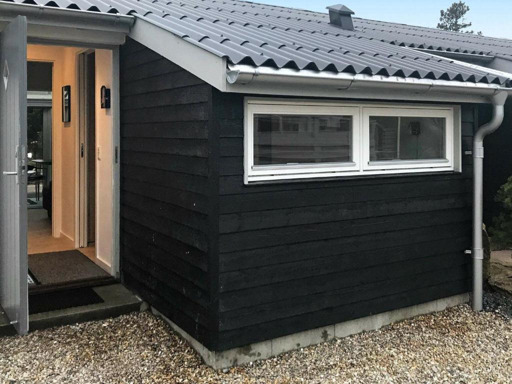 a black building with a window and a door at One-Bedroom Holiday home in Vejers Strand 3 in Vejers Strand