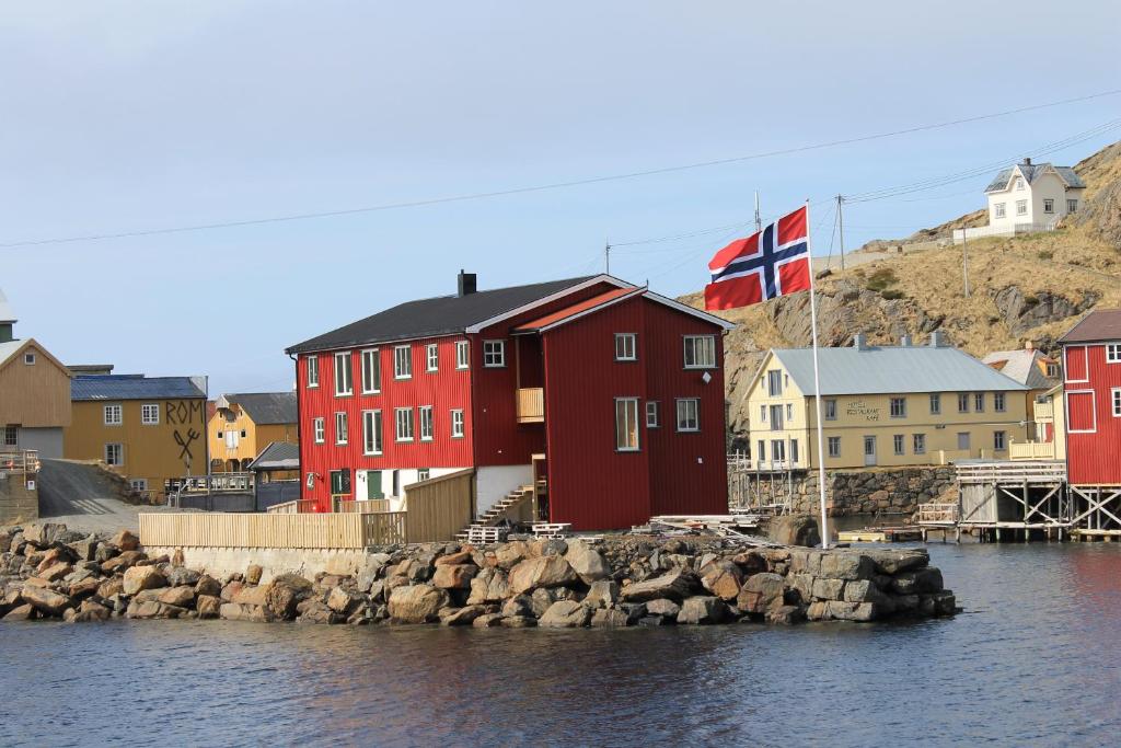 a red building with a british flag next to the water at Nyksund Appartement, Nyksund Brygge in Nyksund
