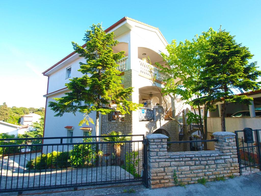 une maison blanche avec une clôture noire et des arbres dans l'établissement Apartments Marija 841, à Pula