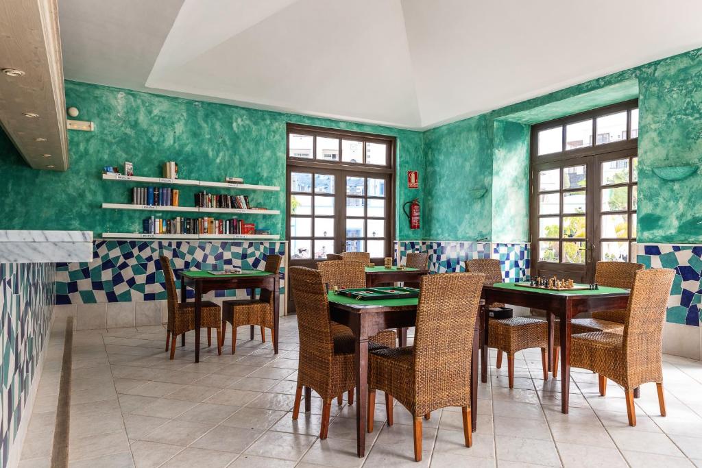a dining room with green walls and tables and chairs at Hotel LIVVO Volcán Lanzarote in Playa Blanca