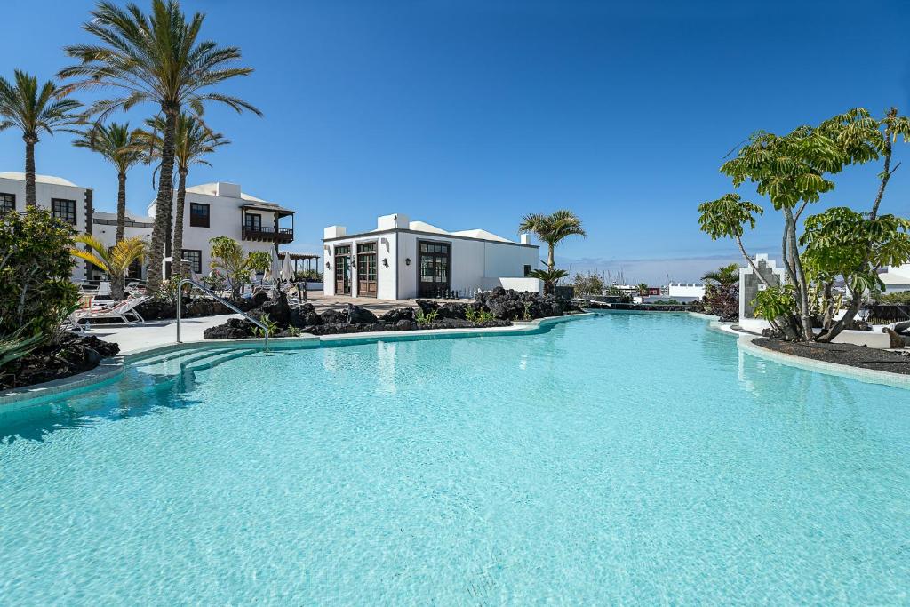 a large swimming pool with palm trees and a building at Hotel LIVVO Volcán Lanzarote in Playa Blanca