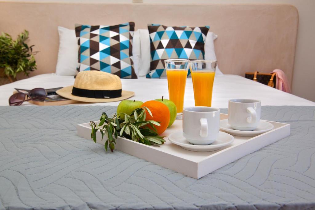 a tray with fruit and two glasses of juice on a bed at Nammos Sunset in Psérimos