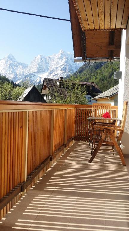 a wooden deck with a table and chairs and mountains at Apartments Katja in Kranjska Gora
