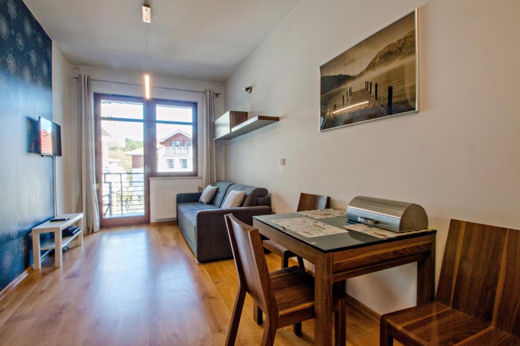 a living room with a table and a couch at Grand Apartments - Neptun Park Maritime Apartment with balcony in Gdańsk