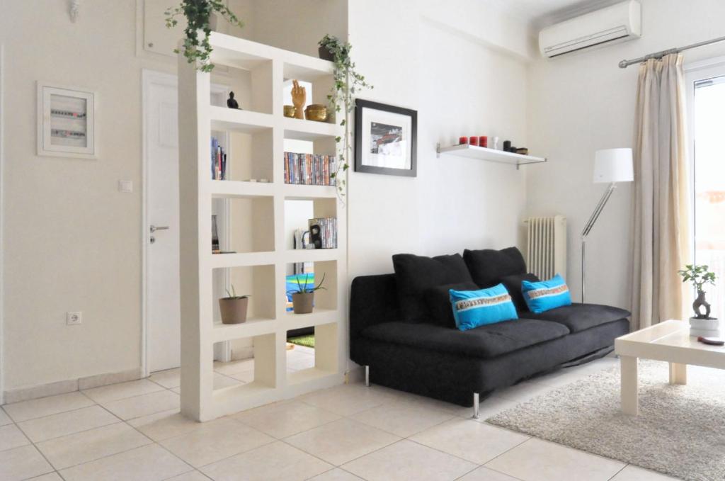 a living room with a black couch and a book shelf at Courtyard Apt - Central Athens in Athens