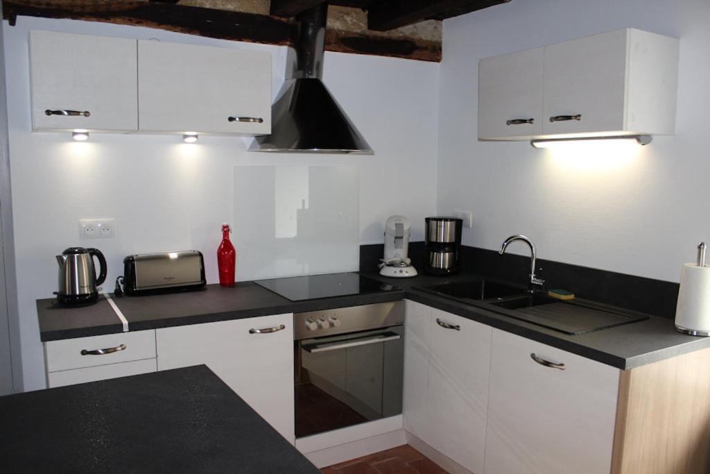 a kitchen with white cabinets and a black counter top at Gite des Celliers in Alise-Sainte-Reine