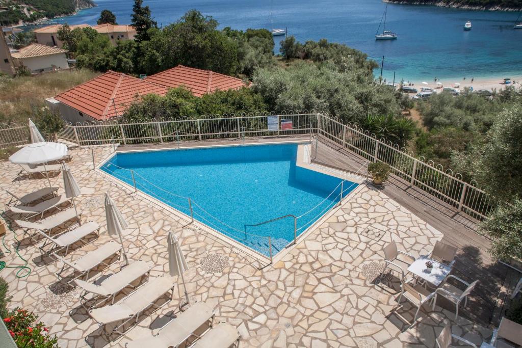 an overhead view of a swimming pool with chairs and a beach at Rouda Village in Mikros Gialos