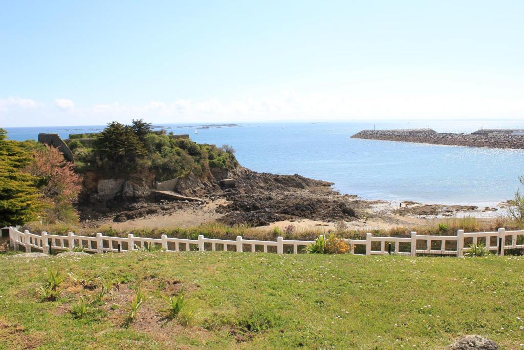 サン・ケ・ポルトリユーにあるAppartement Vue Mer Au Jardin De La Comtesseの海の横の草の丘の上の白い柵