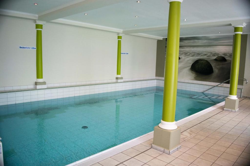 a swimming pool with green columns in a building at Parkhotel Kevelaer in Kevelaer